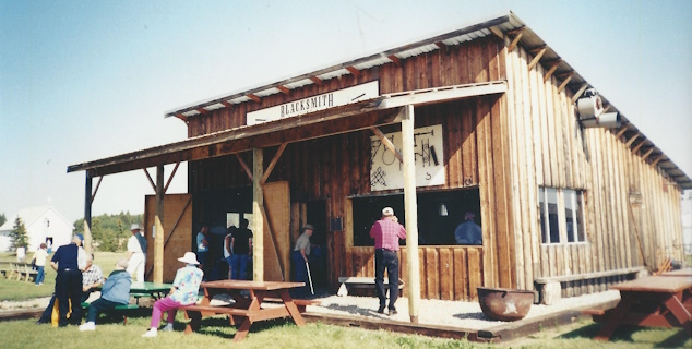 The guild’s blacksmith shop at the Leduc West Antique Society in its early days, with visitors at picnic tables out front